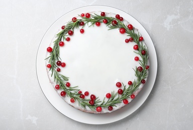 Traditional Christmas cake decorated with rosemary and cranberries on light grey marble table, top view