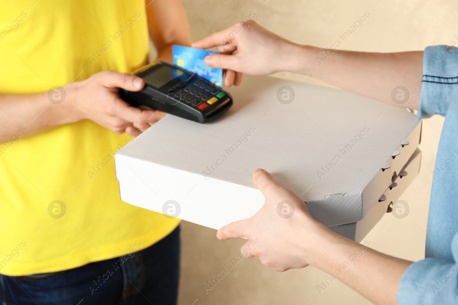Photo of Young woman using bank terminal to pay for food delivery on color background, closeup. Ordering pizza