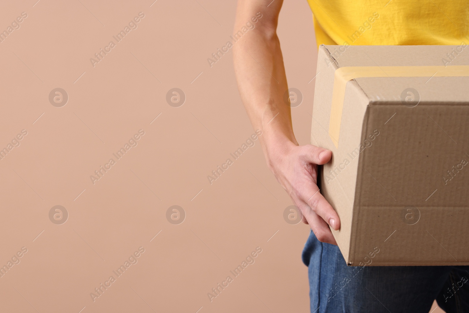 Photo of Courier with parcel on beige background, closeup. Space for text