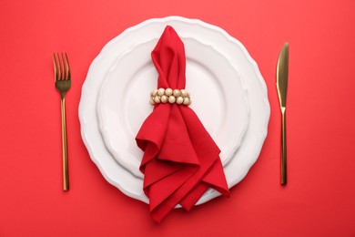 Place setting with napkin on red table, top view