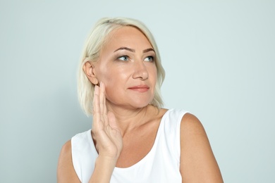 Portrait of mature woman with beautiful face on grey background