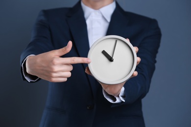 Photo of Businesswoman holding alarm clock on color background. Time concept