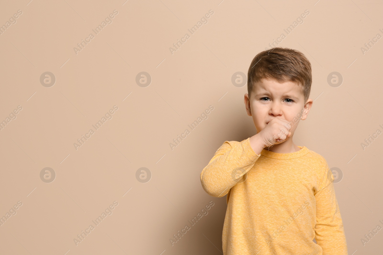 Photo of Cute boy suffering from cough on color background. Space for text