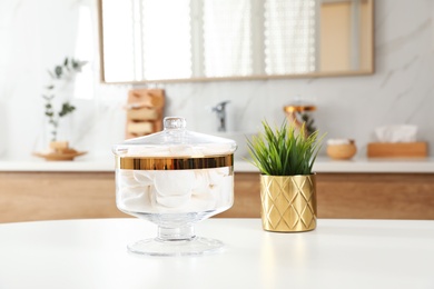 Photo of Jar with cotton pads on table in bathroom