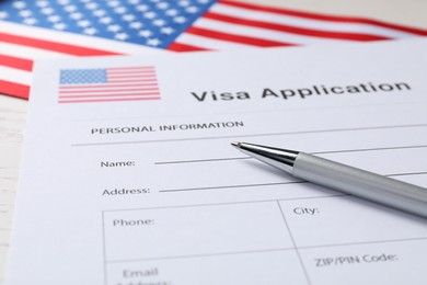 Photo of Immigration to USA. Visa application form, flag and pen on table, closeup