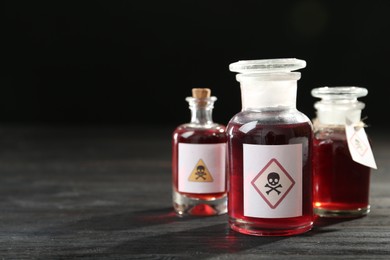 Photo of Bottles with poison on black wooden table. Space for text