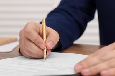 Photo of Man signing document at table, closeup view