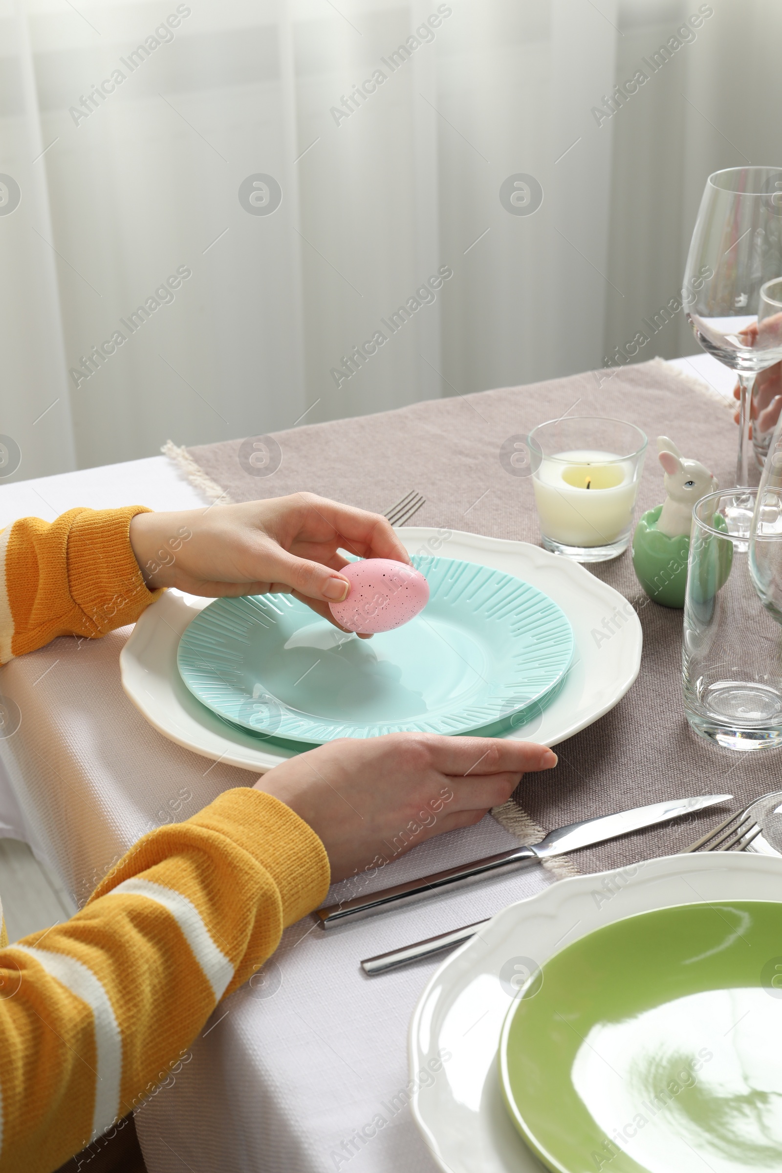 Photo of Woman setting table for festive Easter dinner at home, closeup