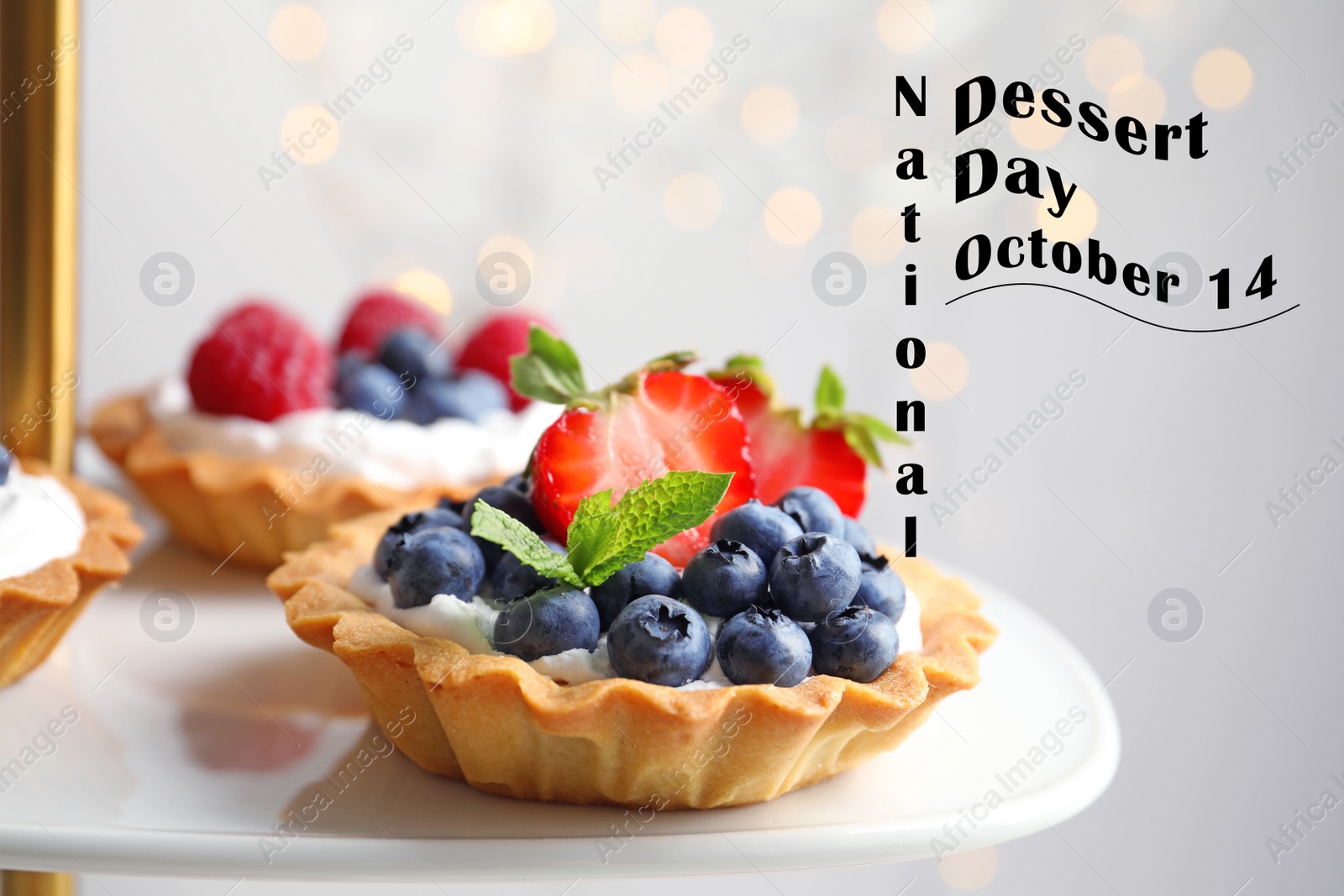 Image of National Dessert Day, October 14. Tasty tartlets with different fresh berries on cake stand