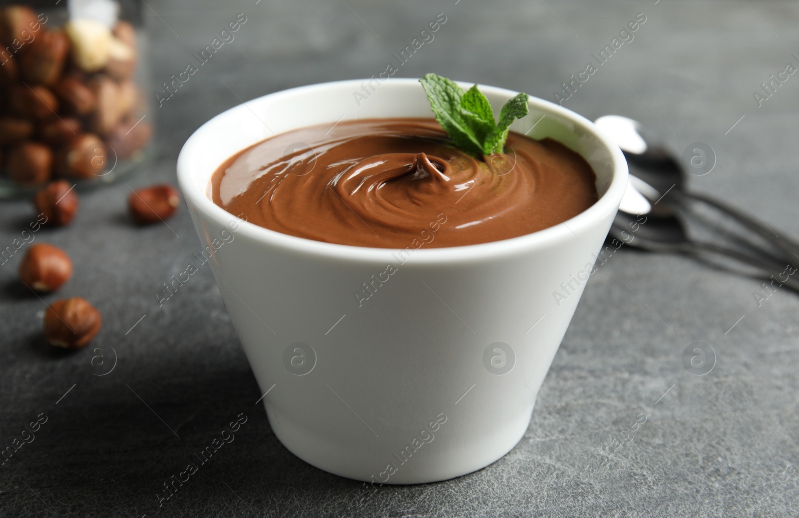 Photo of Ceramic bowl with sweet chocolate cream and mint on table