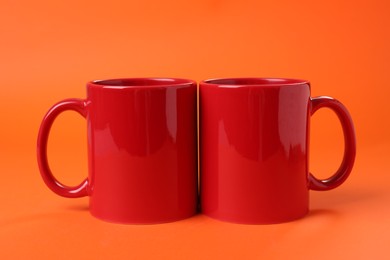 Photo of Two red ceramic mugs on orange background