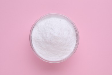 Photo of Bowl of sweet powdered fructose on pink background, top view