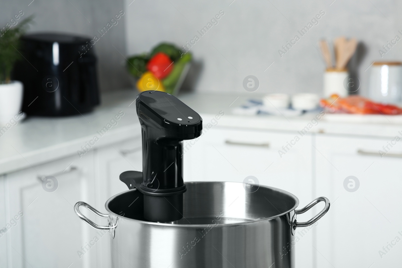 Photo of Pot with sous vide cooker in kitchen, closeup. Thermal immersion circulator