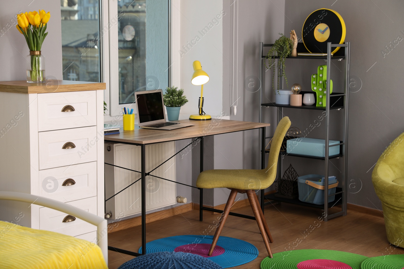 Photo of Comfortable workplace with modern laptop near window in child room. Interior design