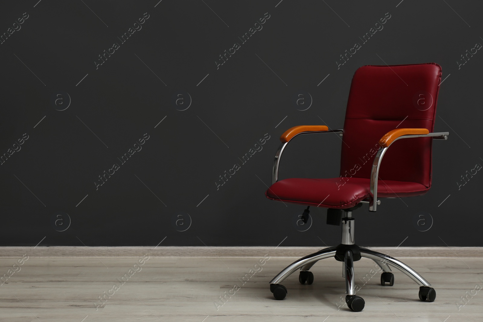 Photo of Comfortable office chair near black wall indoors. Space for text