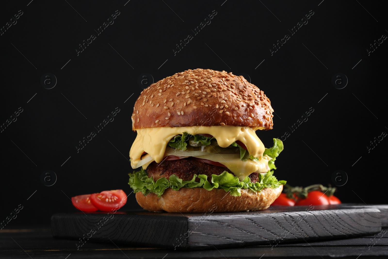 Photo of Vegetarian burger with delicious patty on black wooden table