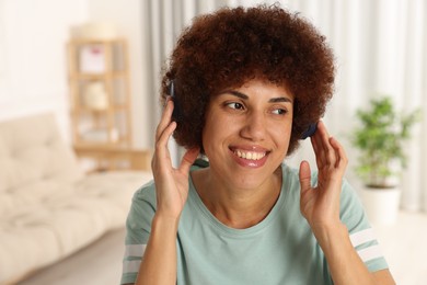 Photo of Happy young woman in headphones enjoying music indoors