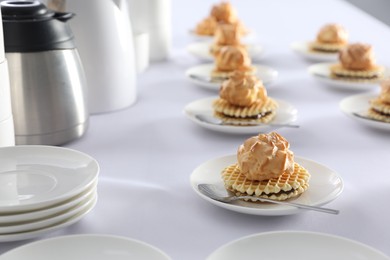 Many delicious waffles with cream served on white table for coffee break