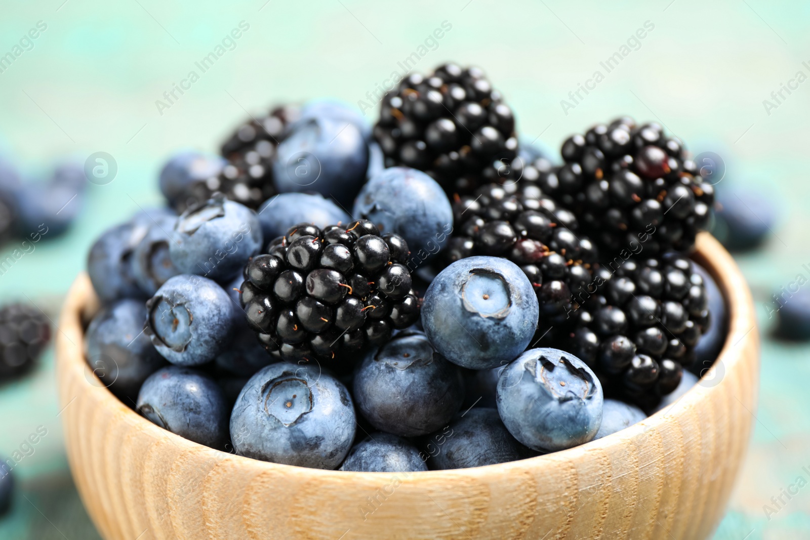 Photo of Blueberries and blackberries wooden in bowl, closeup