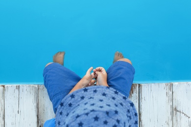 Photo of Little child near outdoor swimming pool, top view. Dangerous situation