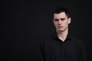 Photo of Portrait of sad man on black background, space for text
