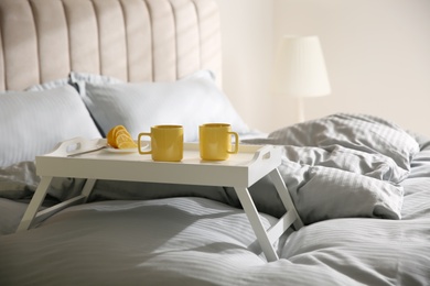 Photo of Soft blanket and tray with breakfast on bed indoors