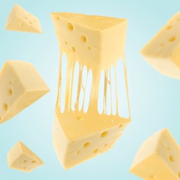 Pieces of cheese falling on light blue background