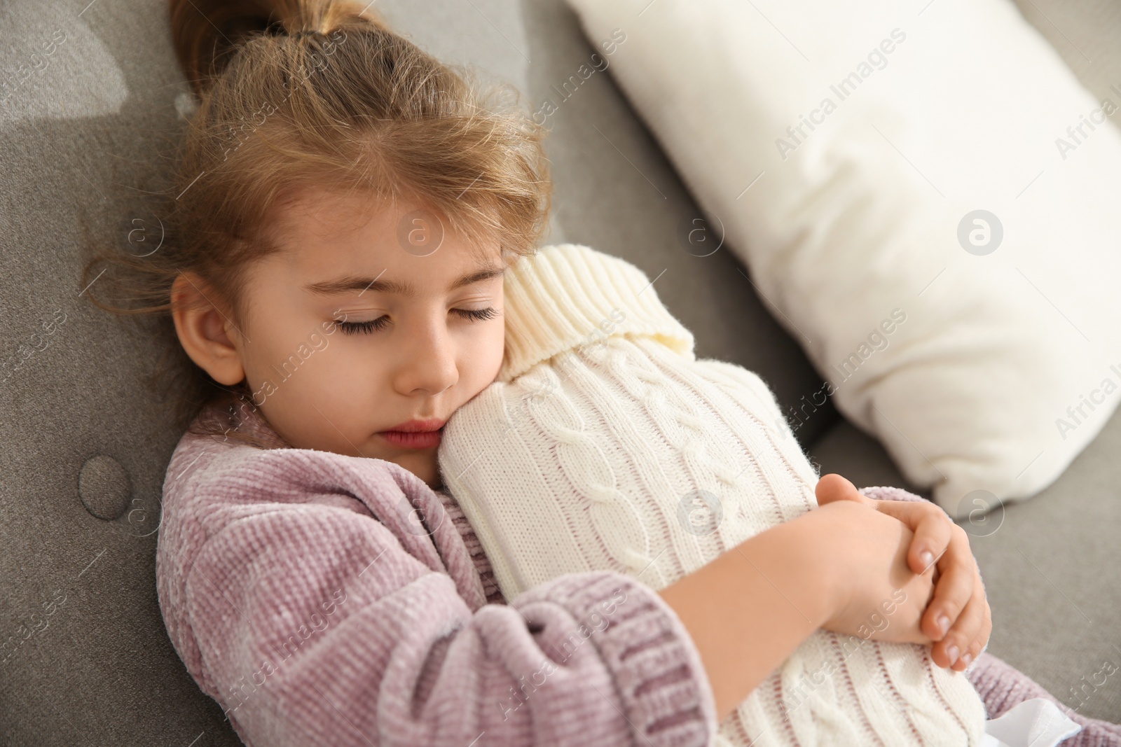 Photo of Ill girl with hot water bottle suffering from cold at home