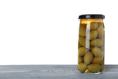 Jar of pickled olives on blue wooden table against white background. Space for text