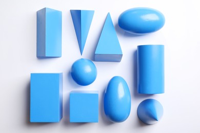 Photo of Set of blue wooden geometrical objects on white background, top view. Montessori toy