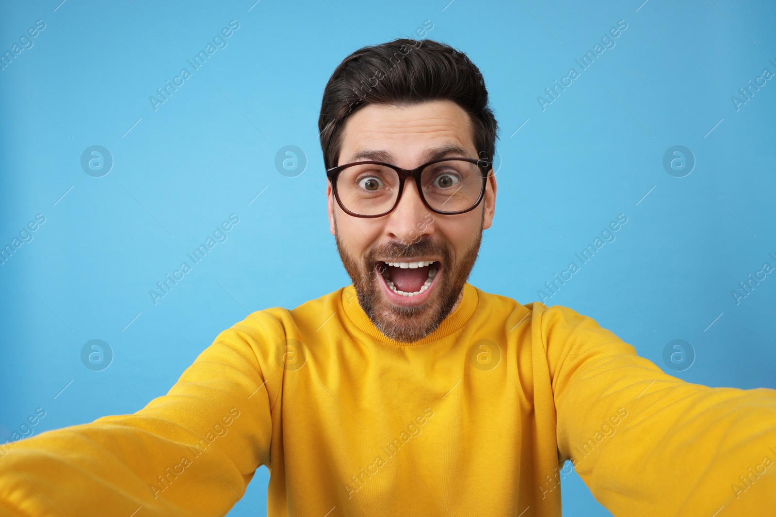 Photo of Happy man taking selfie on light blue background