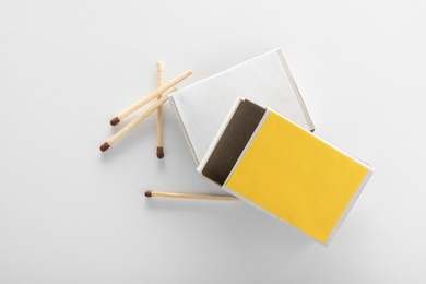 Photo of Cardboard boxes and matches on white background, top view. Space for design