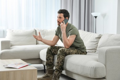 Photo of Soldier talking on phone in living room. Military service