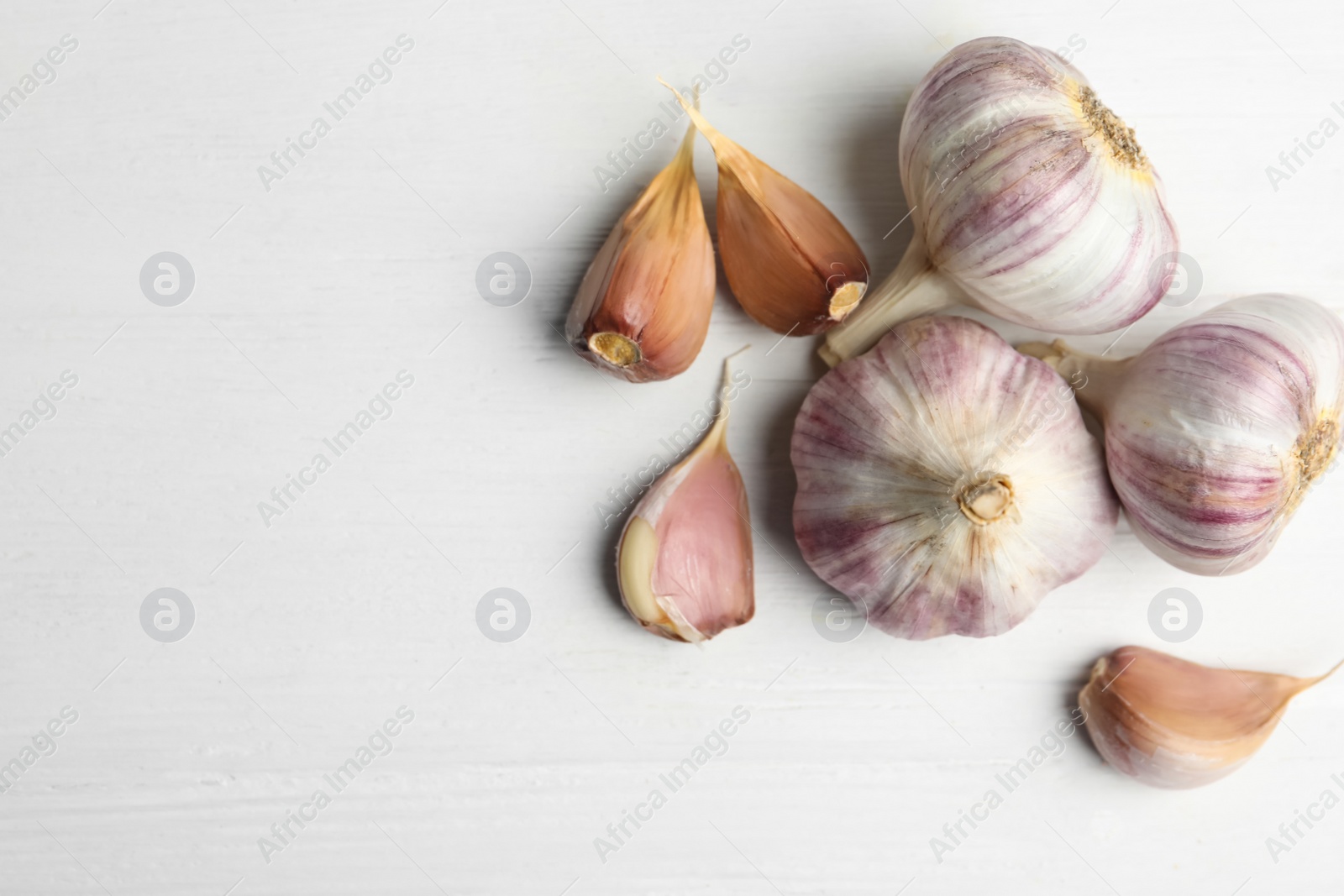 Photo of Fresh organic garlic on white wooden table, flat lay. Space for text