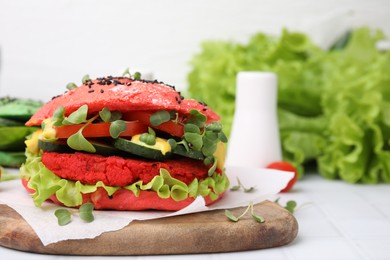 Photo of Tasty pink vegan burger with vegetables, patty and microgreens on white tiled table, closeup. Space for text