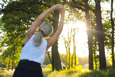 Photo of Woman doing morning exercise in park, back view. Space for text
