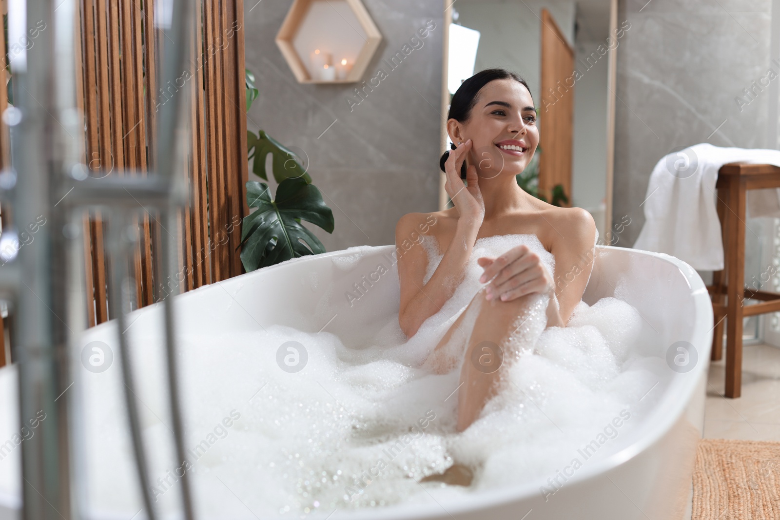 Photo of Beautiful young woman taking bubble bath at home