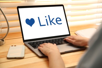 Image of Woman using laptop with word Like on screen at table, closeup