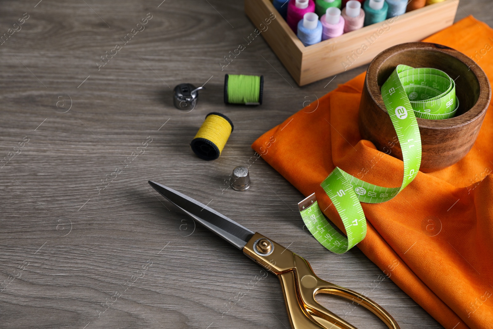 Photo of Set of sewing supplies and accessories on wooden table, space for text