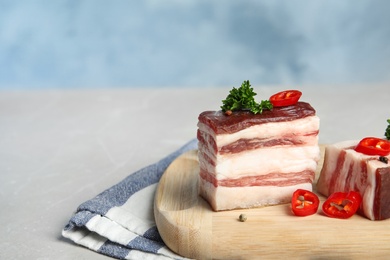 Photo of Board with bacon and pepper on grey table against blue background. Space for text