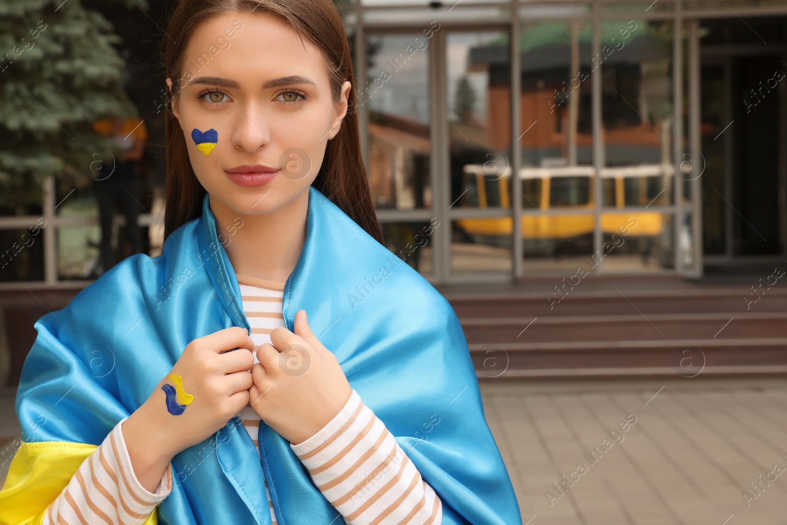 Photo of Young woman with Ukrainian flag outdoors, space for text