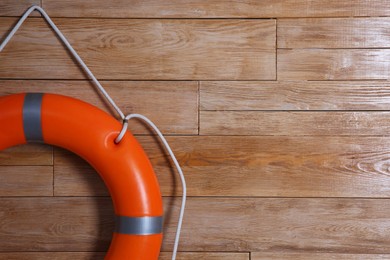 Photo of Orange lifebuoy on wooden background, space for text. Rescue equipment