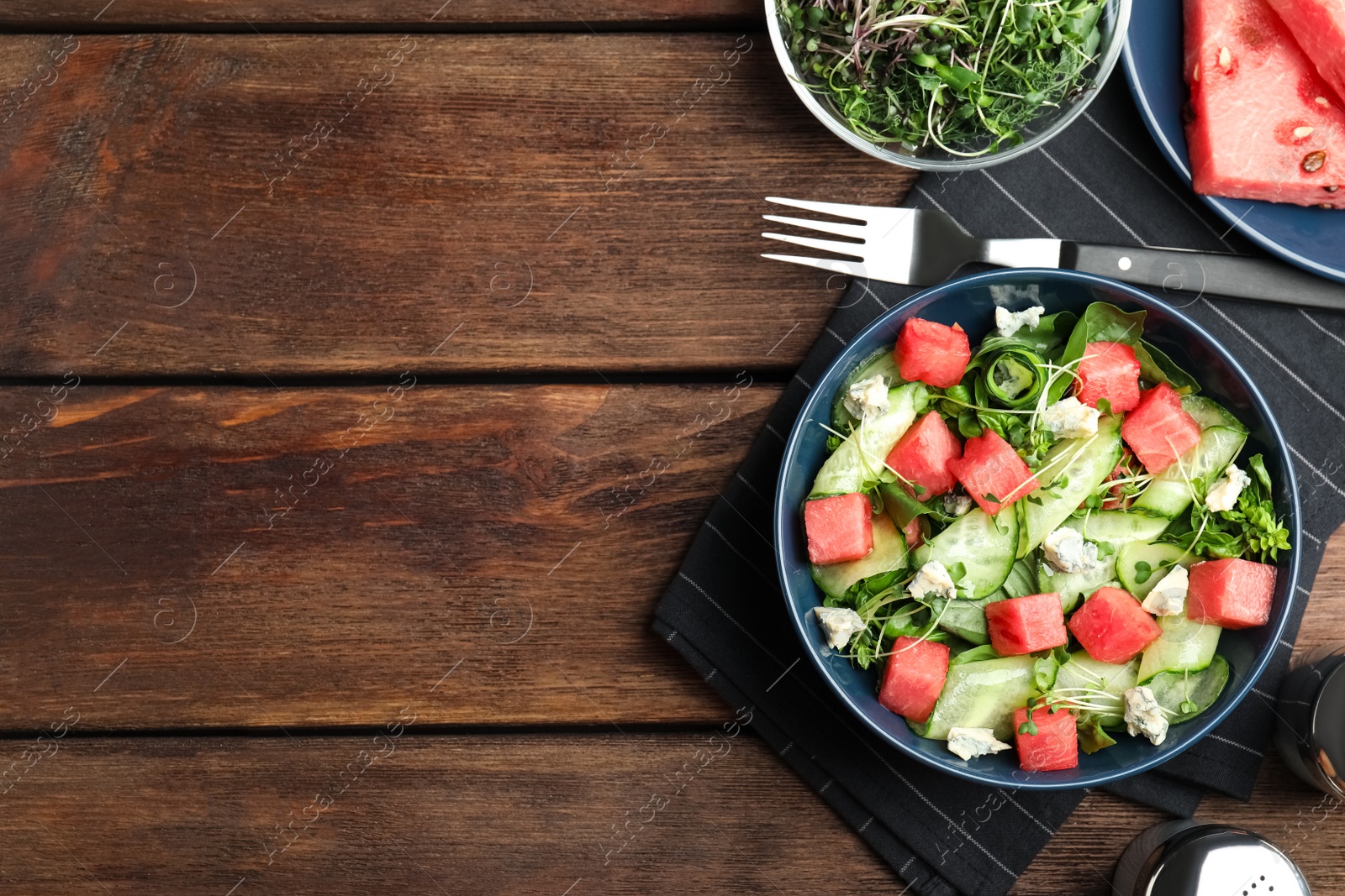 Photo of Delicious salad with watermelon served on wooden table, flat lay. Space for text