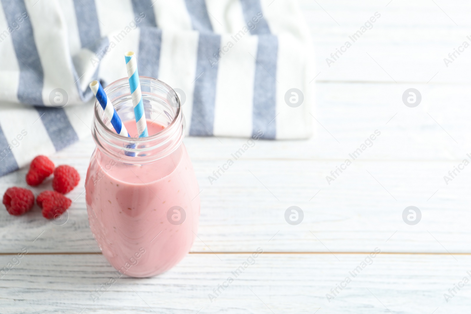 Image of Yummy raspberry smoothie in glass bottle on table. Space for text 