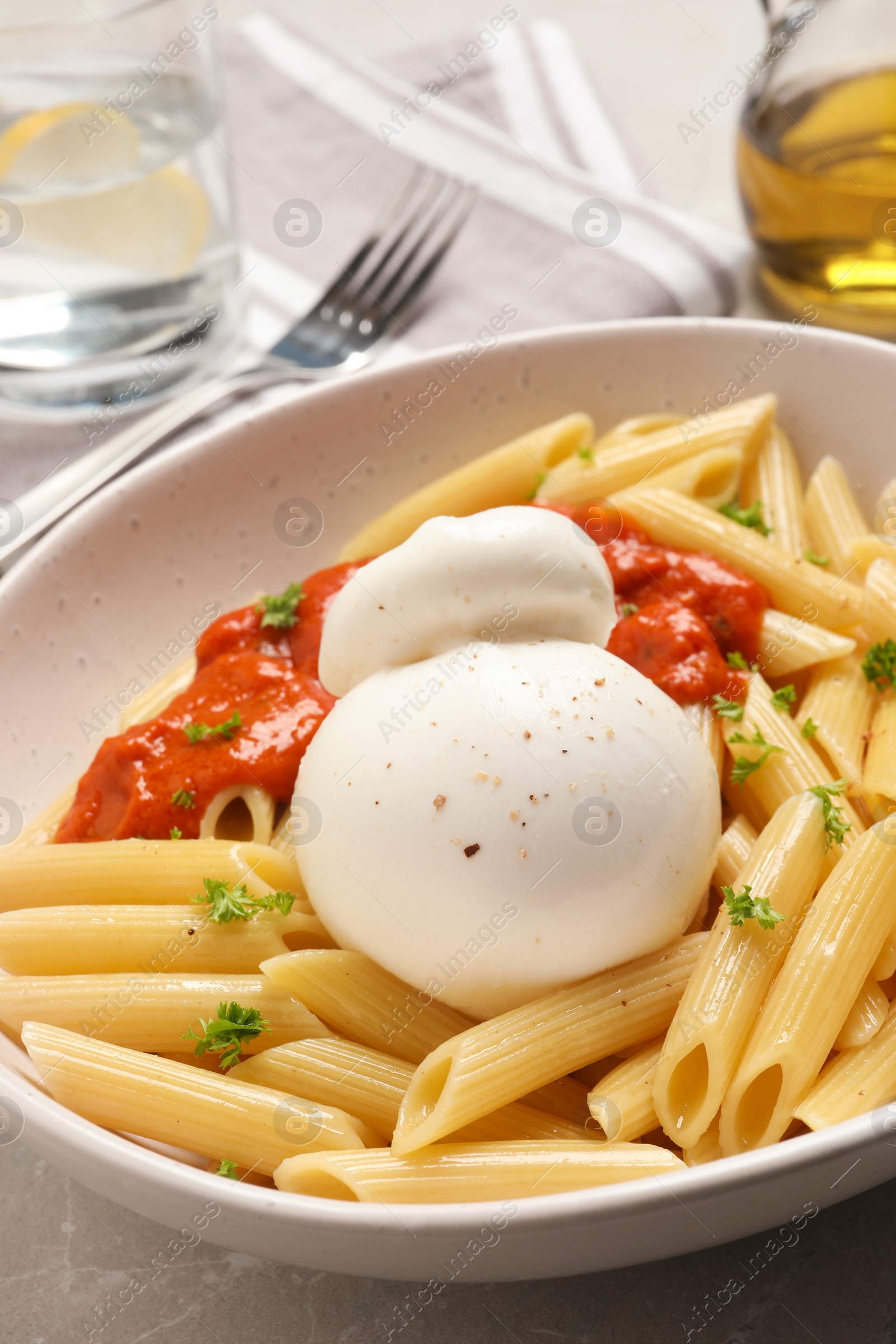 Photo of Delicious pasta with burrata cheese and sauce on light grey table, closeup