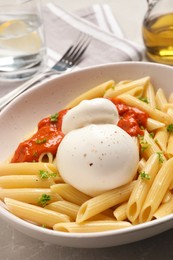 Photo of Delicious pasta with burrata cheese and sauce on light grey table, closeup