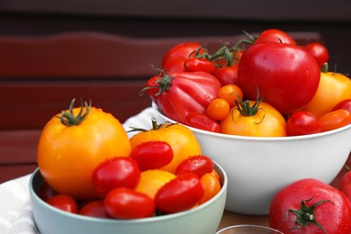 Photo of Bowls with fresh tomatoes and spices on wooden surface, closeup
