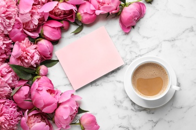 Fragrant peonies, blank card and cup of coffee on marble table, top view with space for text. Spring flowers