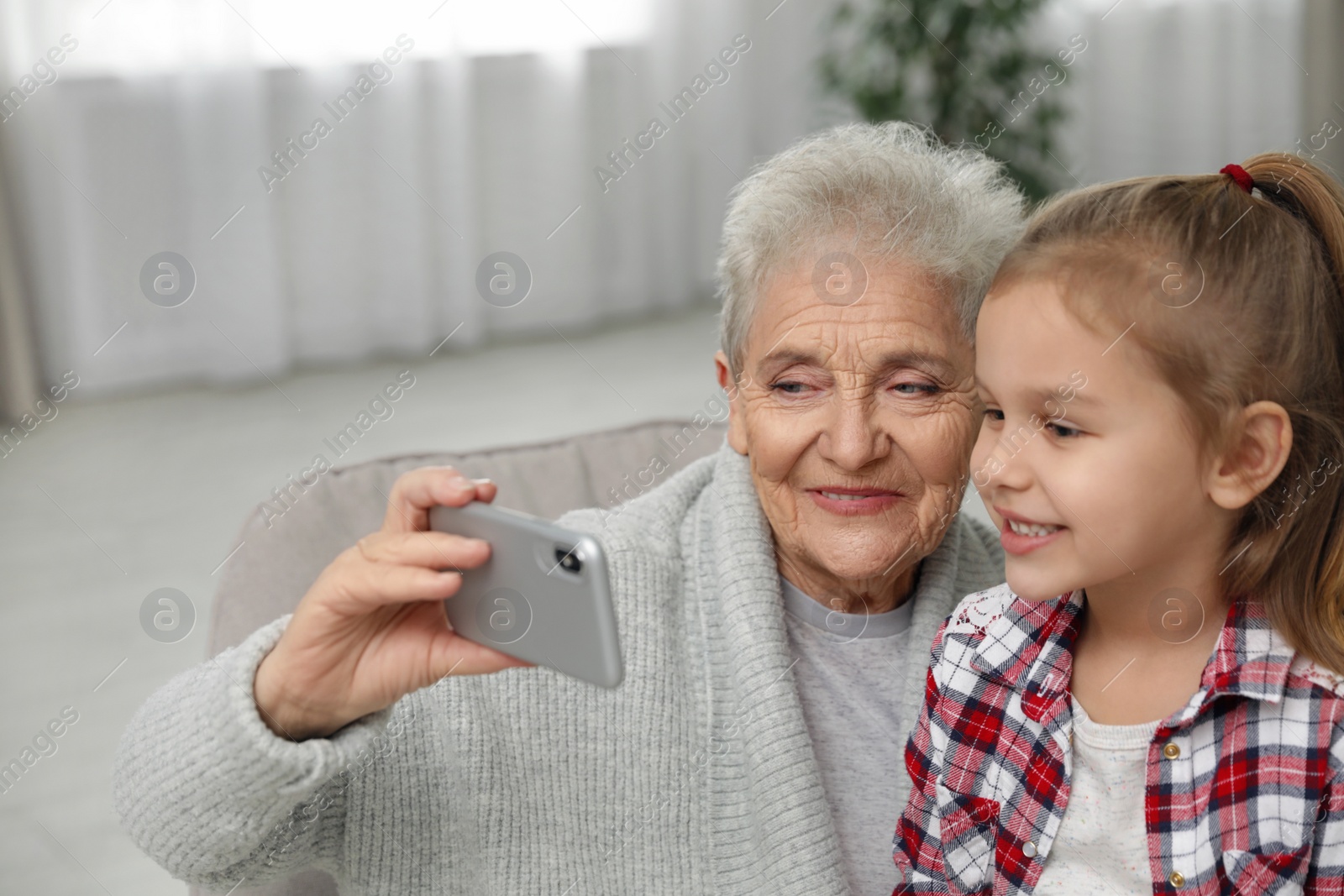 Photo of Cute girl and her grandmother taking selfie  at home