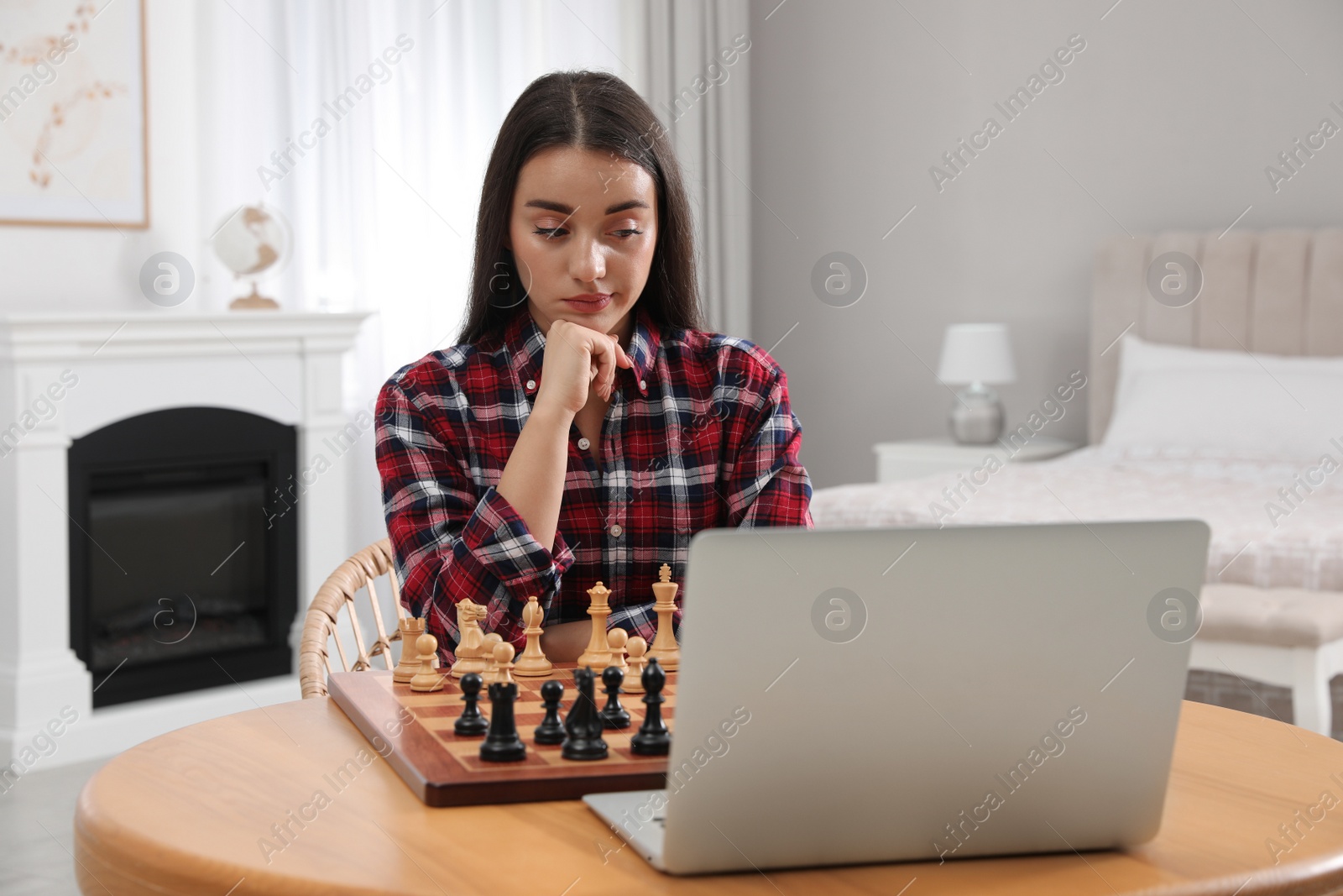 Photo of Thoughtful young woman playing chess with partner through online video chat at home